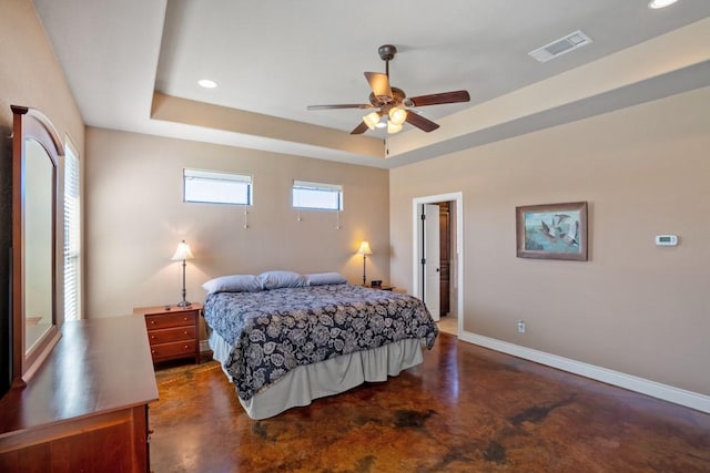 bedroom with a tray ceiling, concrete floors, visible vents, and baseboards