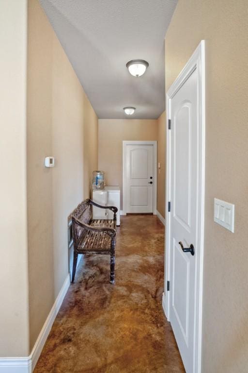 hallway with concrete floors and baseboards