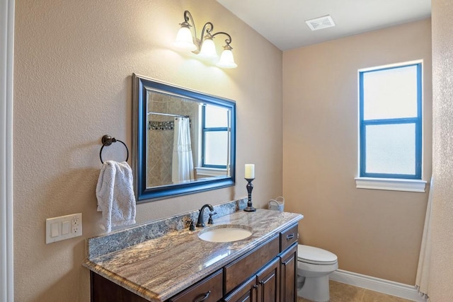 bathroom featuring toilet, visible vents, vanity, baseboards, and tile patterned floors