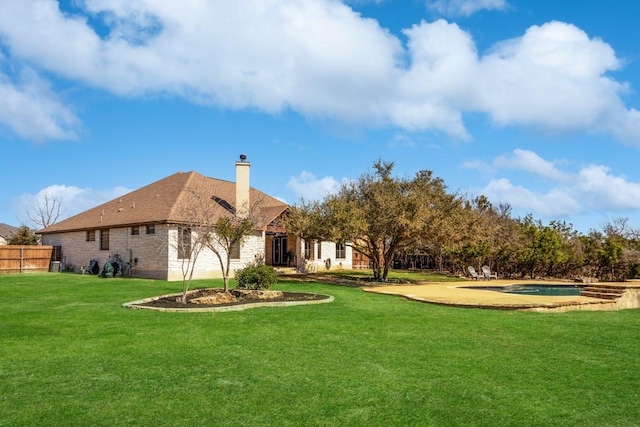 back of house with brick siding, a chimney, a lawn, fence, and an outdoor pool