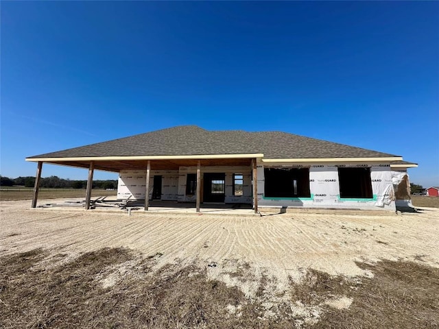 rear view of house featuring roof with shingles