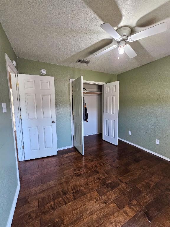 unfurnished bedroom with a closet, visible vents, baseboards, and wood finished floors