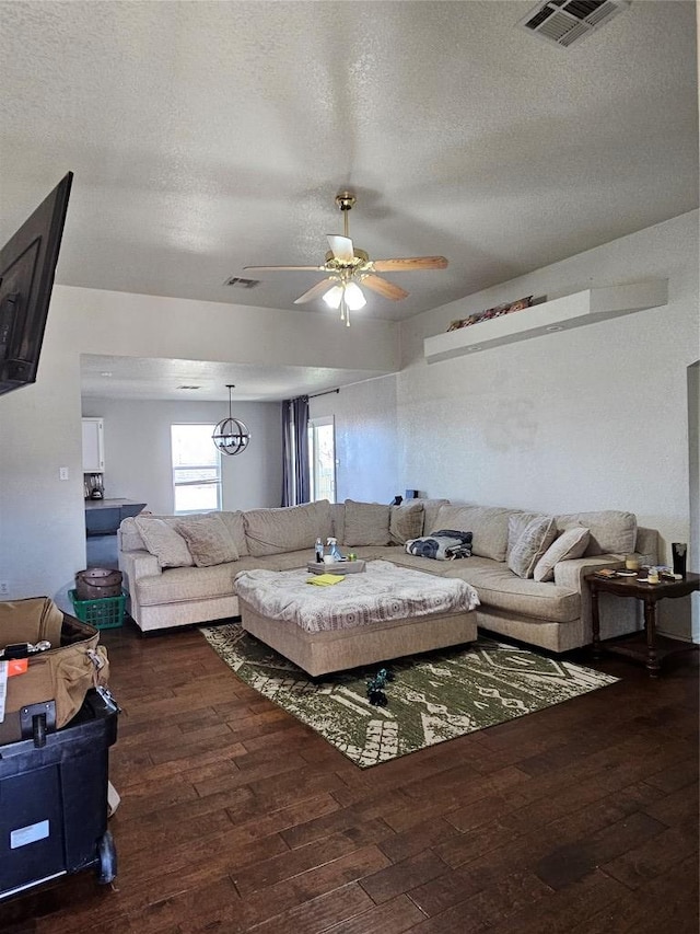 living area with dark wood-style flooring, visible vents, ceiling fan, and a textured ceiling