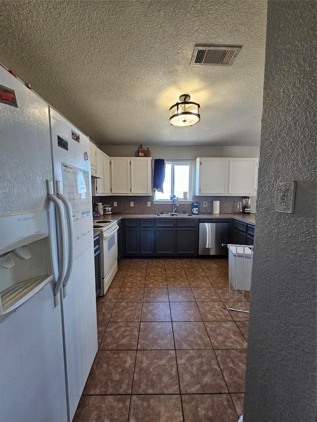 kitchen featuring white appliances, a sink, visible vents, and white cabinetry