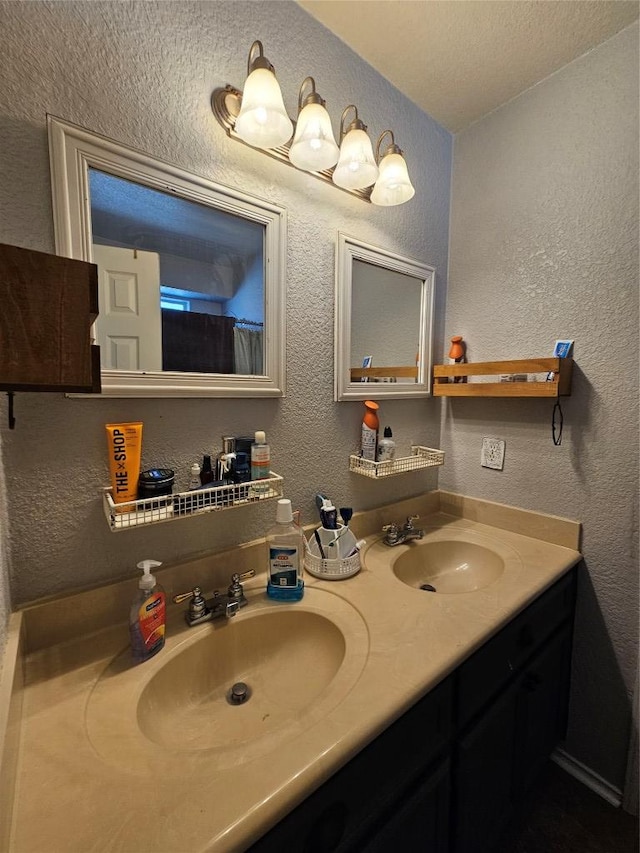 bathroom with double vanity, a sink, and a textured wall