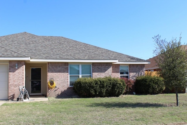 single story home featuring an attached garage, brick siding, roof with shingles, and a front yard