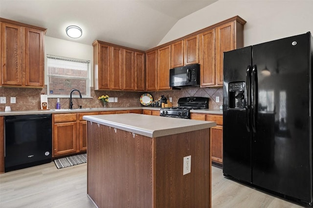 kitchen with brown cabinets, light wood finished floors, vaulted ceiling, a sink, and black appliances