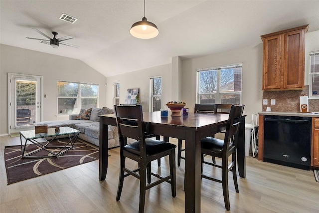 dining space featuring a healthy amount of sunlight, visible vents, vaulted ceiling, and light wood finished floors