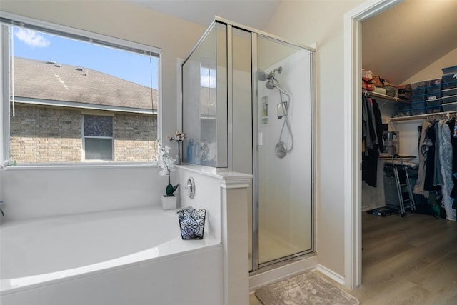 bathroom with a walk in closet, a garden tub, plenty of natural light, and a shower stall