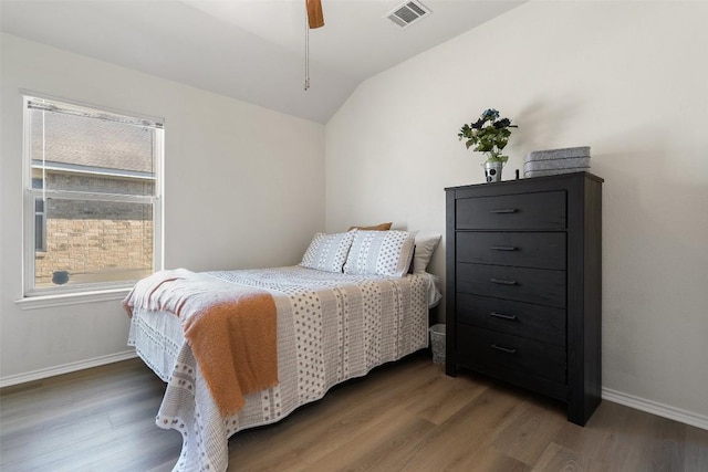 bedroom with vaulted ceiling, wood finished floors, visible vents, and baseboards