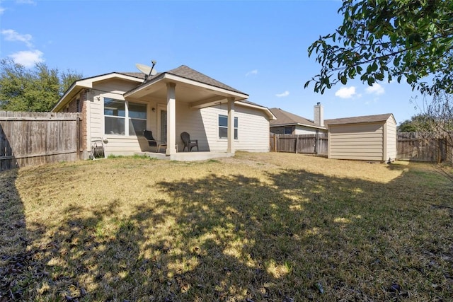 rear view of house featuring a fenced backyard, an outbuilding, a yard, a patio area, and a shed