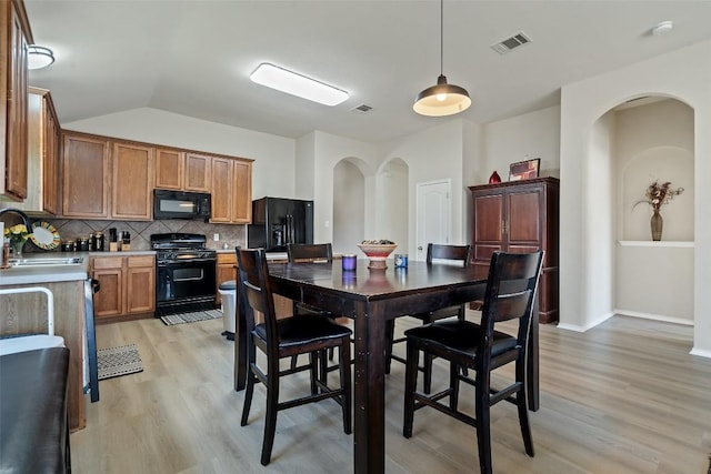 kitchen featuring arched walkways, visible vents, decorative backsplash, a sink, and black appliances