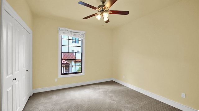 unfurnished bedroom featuring carpet floors, ceiling fan, baseboards, and a closet