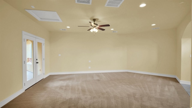 carpeted empty room with baseboards, visible vents, arched walkways, and recessed lighting