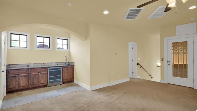 interior space with beverage cooler, light carpet, a sink, and visible vents