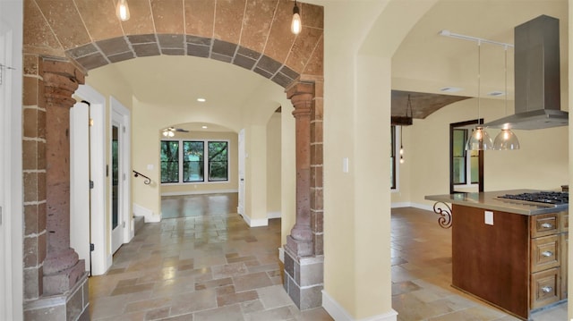 corridor with arched walkways, baseboards, and stone tile floors