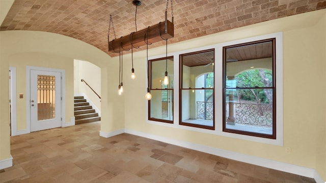 spare room featuring baseboards, arched walkways, stairway, brick ceiling, and vaulted ceiling