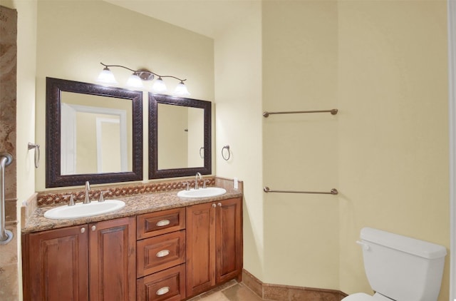 bathroom featuring toilet, double vanity, and a sink