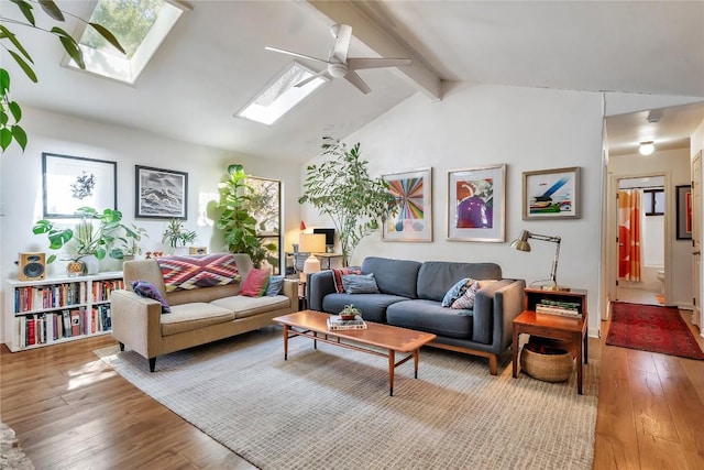 living room featuring lofted ceiling with skylight, wood-type flooring, and a ceiling fan