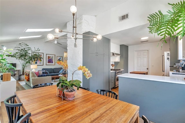 dining room featuring lofted ceiling with skylight, wood finished floors, and visible vents