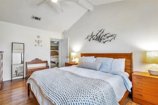 bedroom with lofted ceiling with beams, a ceiling fan, visible vents, and wood finished floors