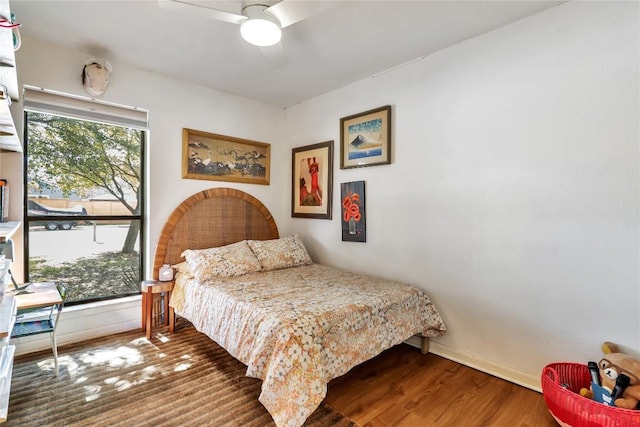 bedroom featuring wood finished floors, a ceiling fan, and baseboards