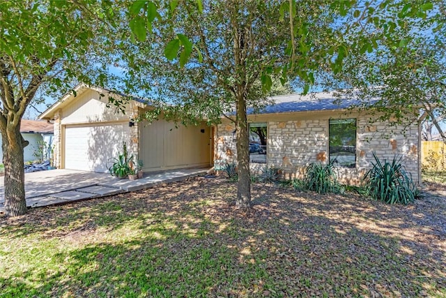 ranch-style home with a garage, stone siding, and concrete driveway