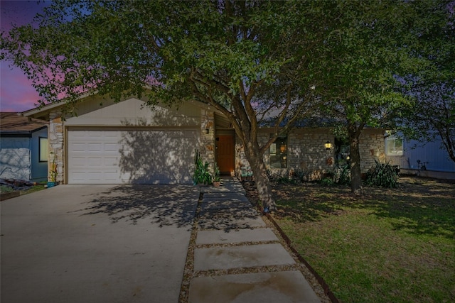 view of front of house with a garage, stone siding, a yard, and driveway