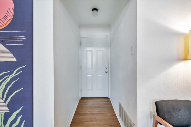 corridor with wood finished floors, visible vents, and baseboards