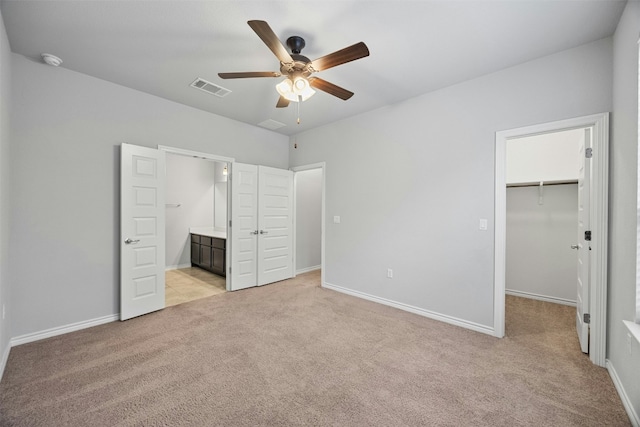 unfurnished bedroom with light colored carpet, visible vents, a spacious closet, and baseboards