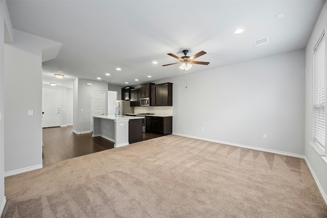 kitchen with a center island with sink, dark colored carpet, visible vents, appliances with stainless steel finishes, and open floor plan