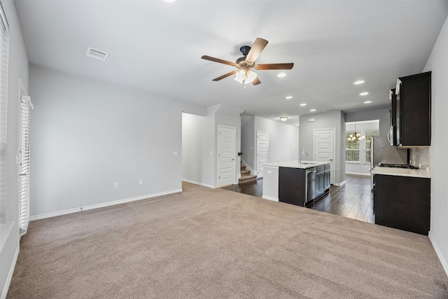 unfurnished living room with visible vents, stairway, ceiling fan with notable chandelier, dark carpet, and recessed lighting