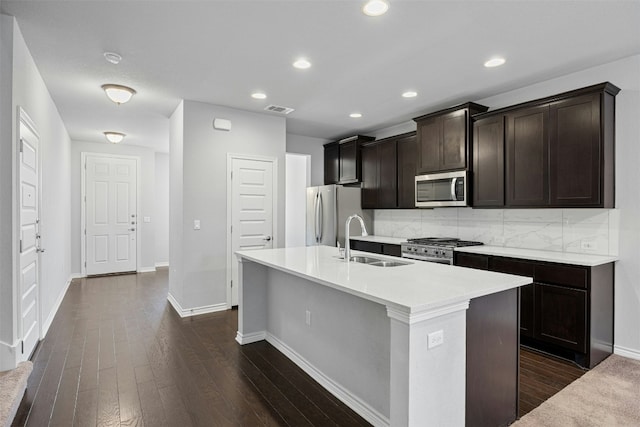 kitchen with stainless steel appliances, dark wood finished floors, a sink, and visible vents