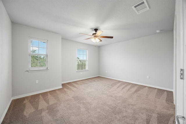 carpeted spare room featuring baseboards, a textured ceiling, visible vents, and a ceiling fan