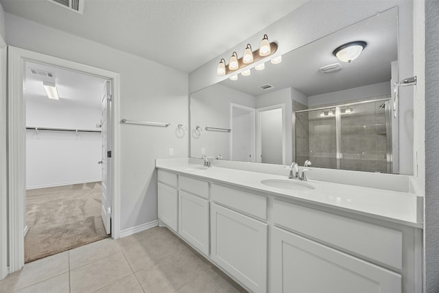 full bath featuring double vanity, a sink, visible vents, and a shower stall