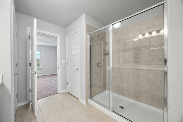 bathroom featuring tile patterned flooring, baseboards, a shower stall, and a textured ceiling