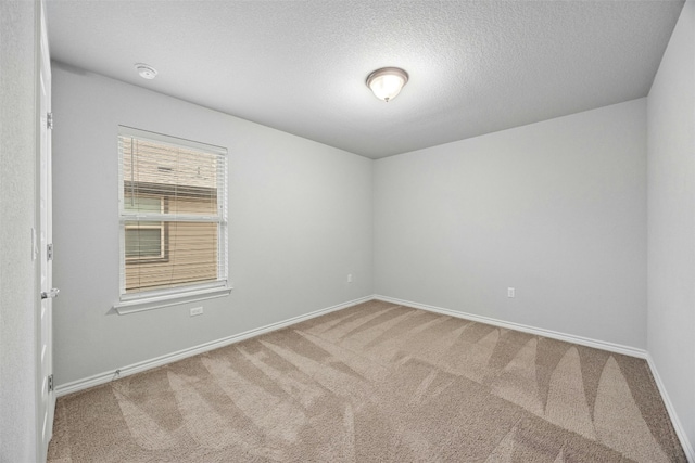 carpeted spare room with a textured ceiling and baseboards