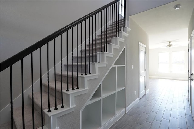 stairway with ceiling fan, baseboards, and wood finished floors