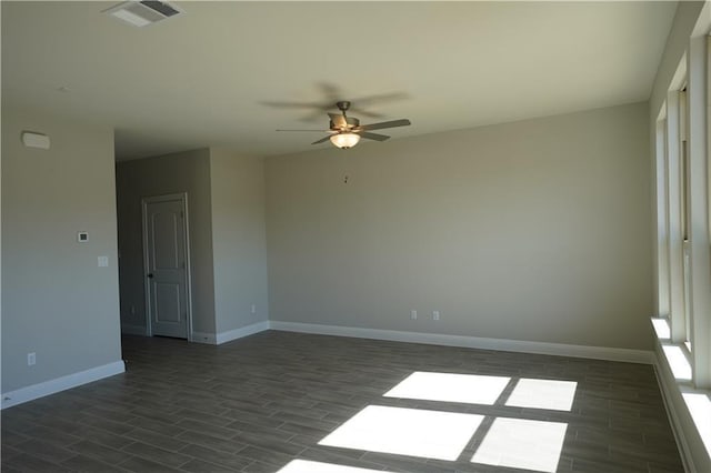 spare room with ceiling fan, baseboards, visible vents, and dark wood finished floors