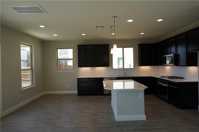 kitchen with stainless steel appliances, visible vents, a sink, a kitchen island, and plenty of natural light