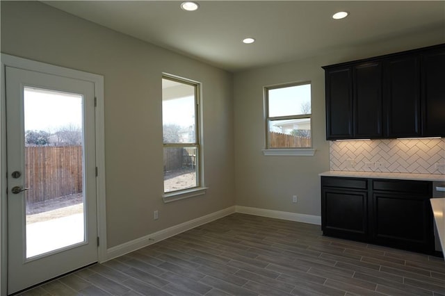 interior space featuring tasteful backsplash, baseboards, light countertops, and wood finished floors