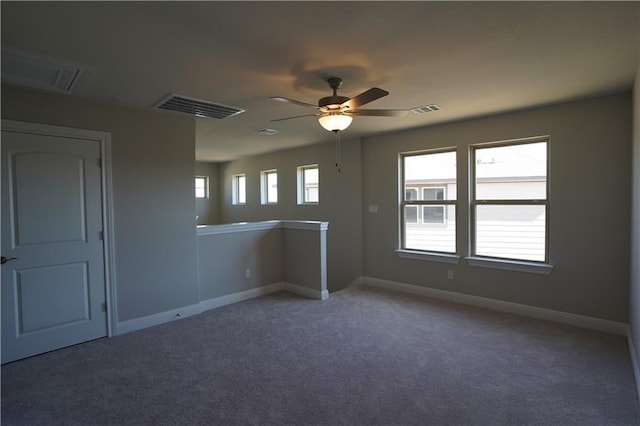 carpeted spare room with baseboards, visible vents, and a ceiling fan