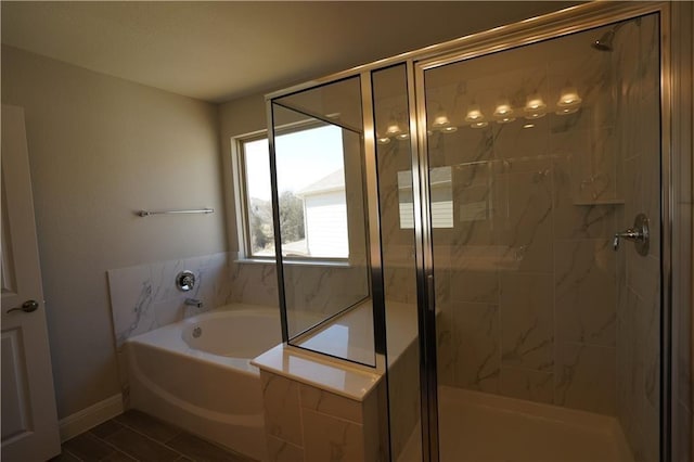 bathroom with a shower stall, baseboards, and a bath