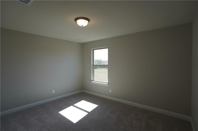 unfurnished room featuring dark colored carpet, visible vents, and baseboards