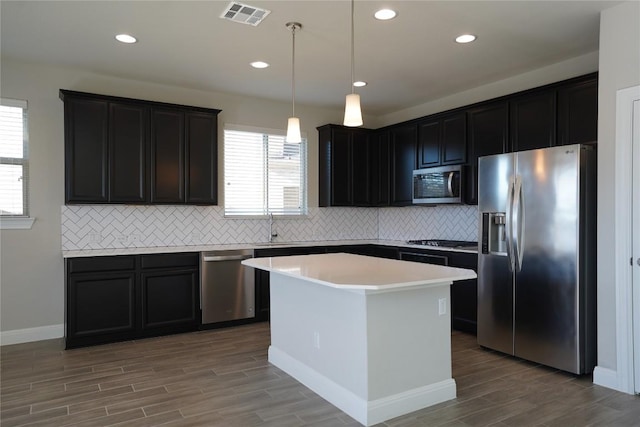 kitchen featuring wood finish floors, a sink, visible vents, appliances with stainless steel finishes, and a center island