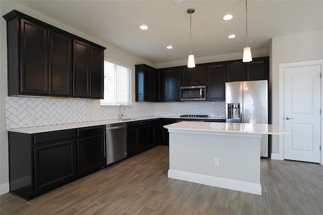 kitchen with stainless steel appliances, light countertops, a sink, and wood finished floors