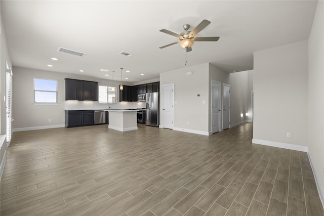 unfurnished living room featuring a ceiling fan, light wood-style floors, visible vents, and baseboards