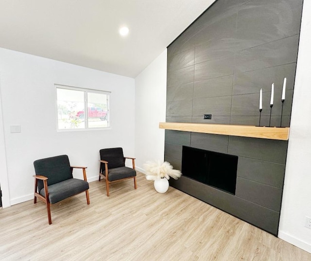 living area with a fireplace, baseboards, and wood finished floors