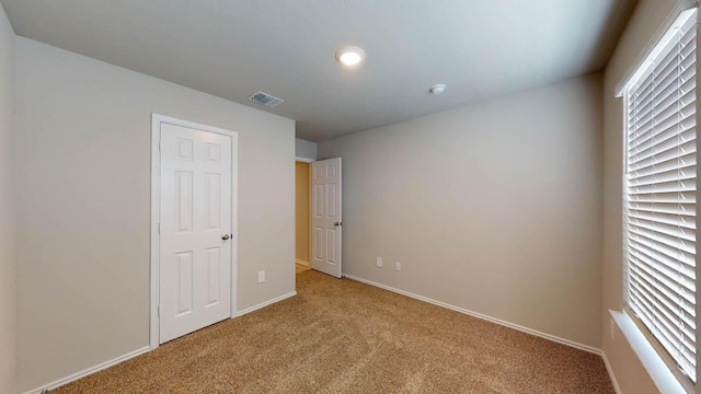 unfurnished bedroom featuring light colored carpet, visible vents, and baseboards