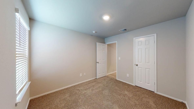 unfurnished bedroom with baseboards, multiple windows, visible vents, and carpet flooring